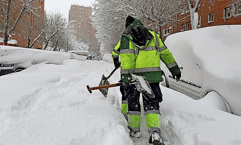 Varios operarios retiran la nieve en el barrio madrileño de Vallecas para hacer un camino por el que se pueda transitar. 